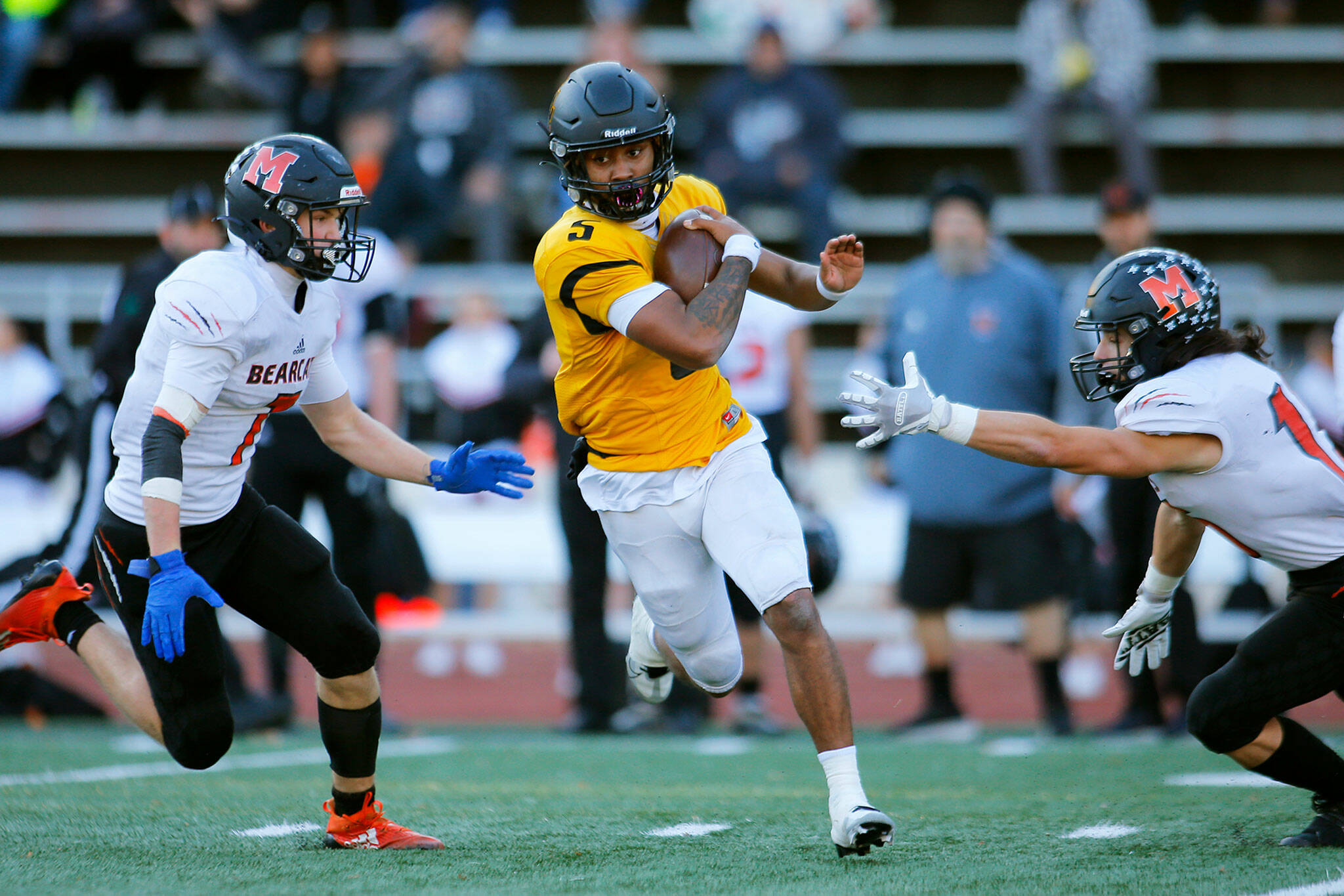Lincoln’s Gabarri Johnson splits two defenders on a long scramble during a playoff matchup against Monroe on Saturday, Nov. 12, 2022, at the Lincoln Bowl in Tacoma, Washington. (Ryan Berry / The Herald)