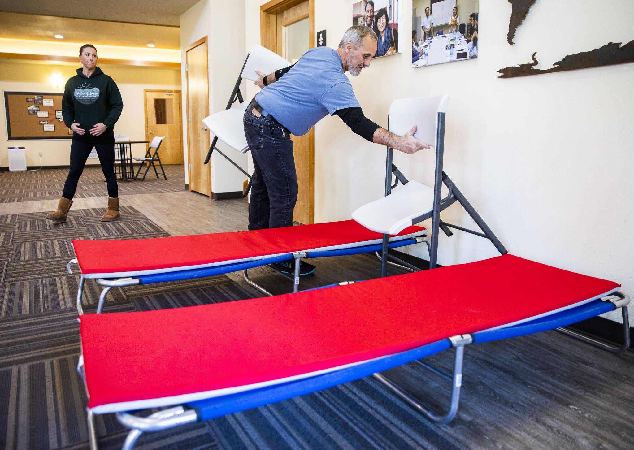 Roger Evans, New Hope Fellowship Church shelter coordinator, sets up two cots as examples of what is available to those that seek shelter at the church on Tuesday, in Monroe. (Olivia Vanni / The Herald)