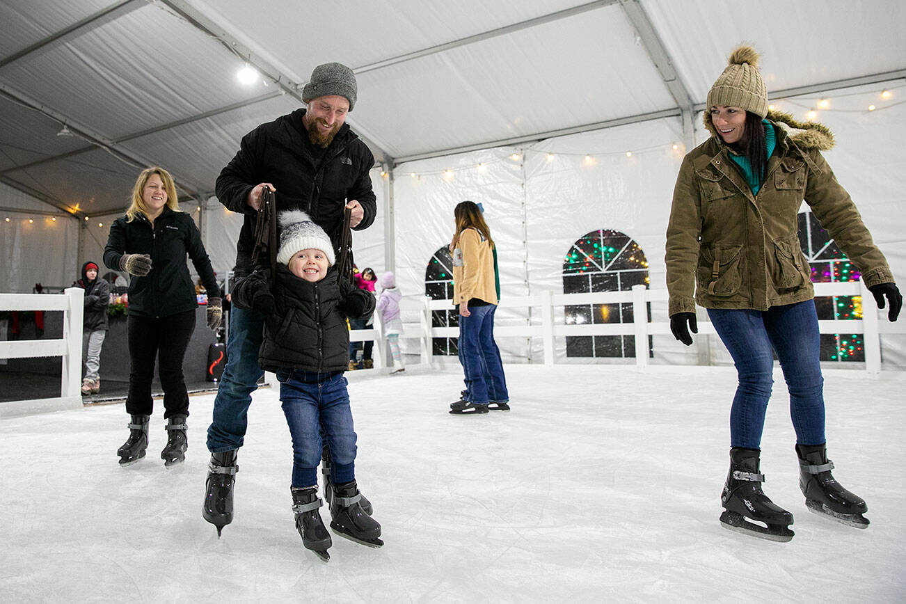 Josh and Nicki Haine help their 4-year-old niece Eleanor get around on skates for the first time as her mother Tiffany Butler, left, follows in tow on the opening night of Arlington’s new seasonal ice rink Friday, Nov. 18, 2022, at Legion Memorial Park in downtown Arlington, Washington. (Ryan Berry / The Herald)