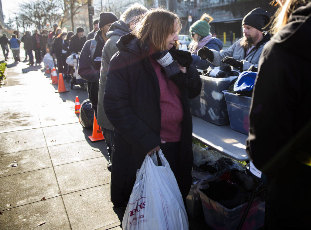 People line up to get gloves, hats and their choice of a sleeping bag or a ShelterSuit from Angel Resource Connection at the Carnegie Resource Center on Wednesday in Everett. (Olivia Vanni / The Herald)
