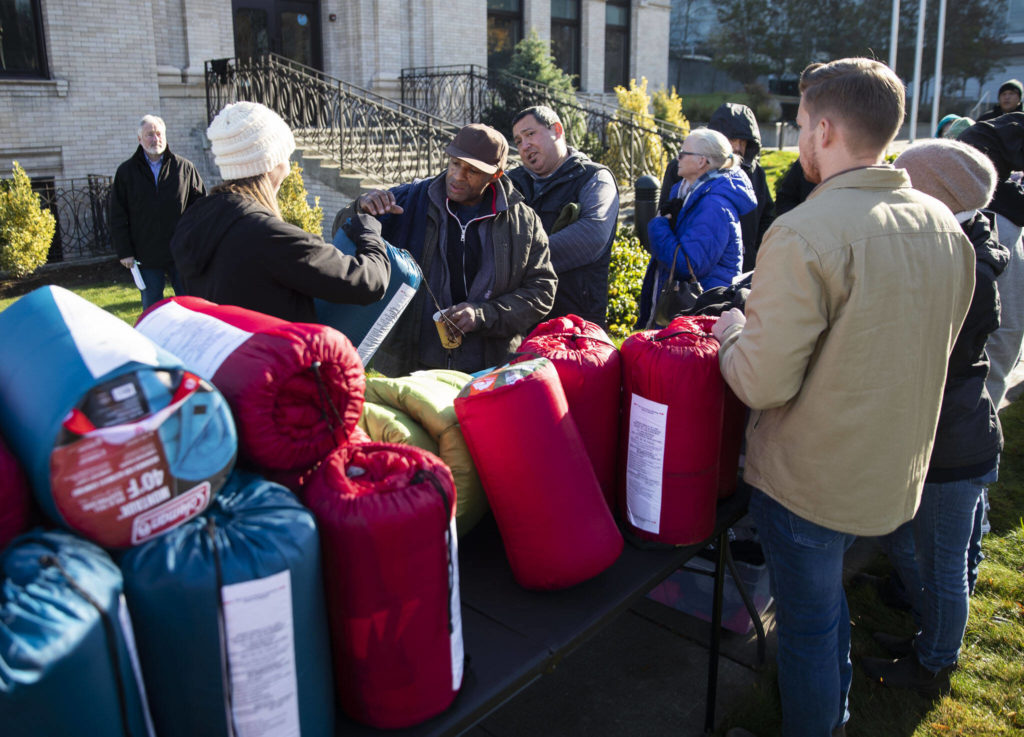 People get their choice of a sleeping bag or a ShelterSuit from Angel Resource Connection at the Carnegie Resource Center on Wednesday, in Everett. (Olivia Vanni / The Herald) 

