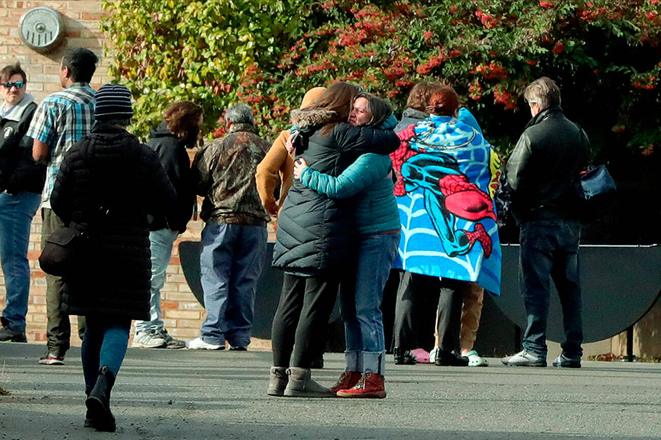 Parents comfort each other outside of Ingraham High School after reports of a school shooting in Seattle, on Tuesday, Nov. 8, 2022. A student who was shot at the Seattle high school has died and a suspect is in custody, officials said. (Greg Gilbert/The Seattle Times via AP)