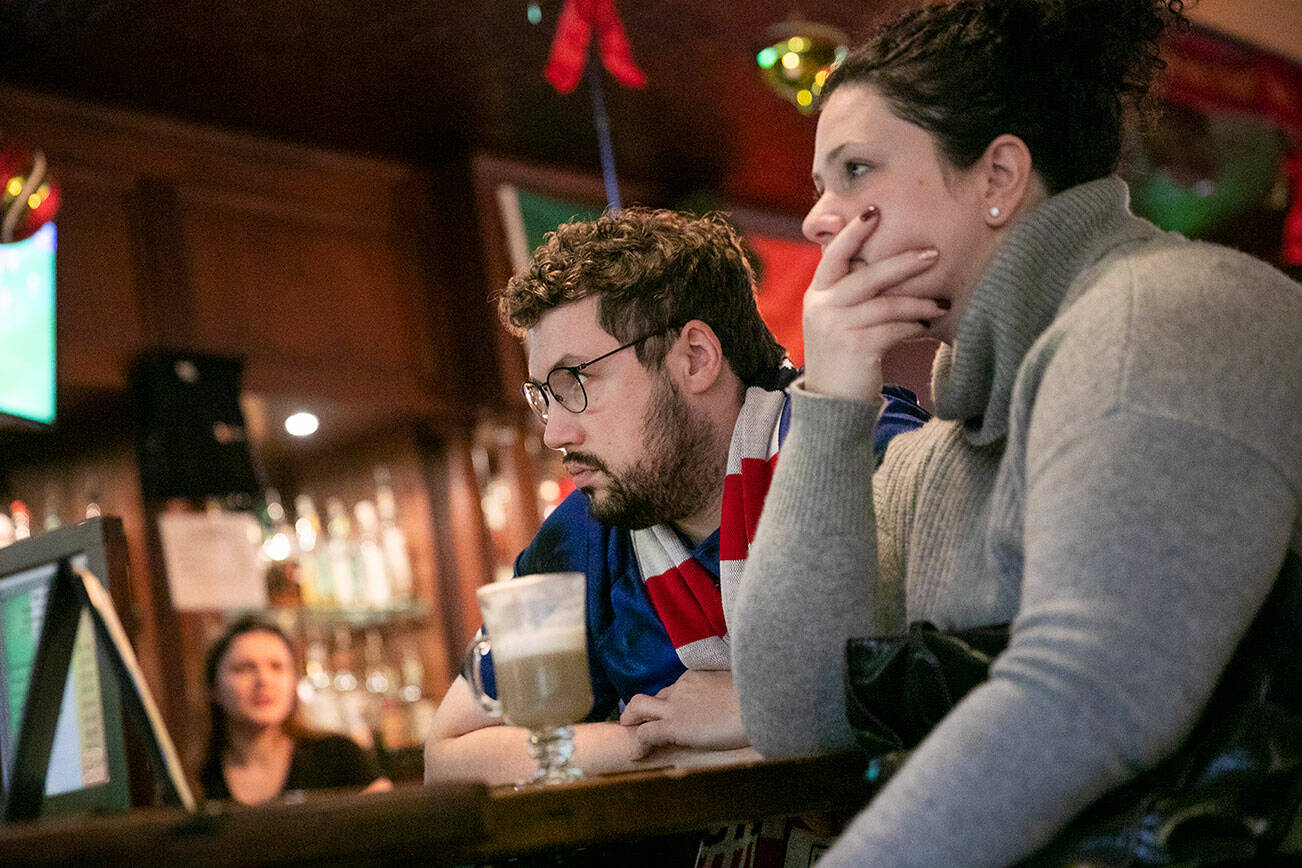 Luke Sayler and Claire Murphy stress out while watching the World Cup at the Irishmen Pub as the U.S. nearly gives up a last-minute goal during their 0-0 draw with England on Friday, Nov. 25, 2022, in Everett, Washington. (Ryan Berry / The Herald)