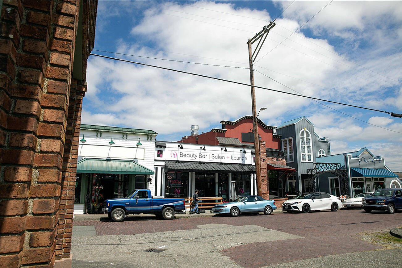 Vehicles are parked in front boutique-style businesses on the brick road portion of 270th Street on Friday, July 22, 2022, in Historic West Downtown in Stanwood, Washington. (Ryan Berry / The Herald)