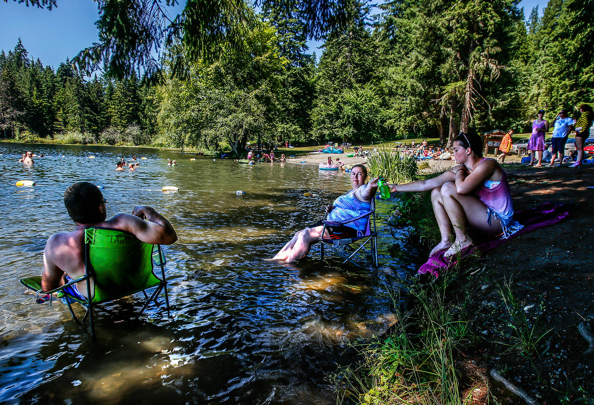 Sonny Taulbee, left, his wife, Carissa and daughter, Ashlyn, 14, beat the heat in their lawn chairs in July 2018, at Lake Roesiger County Park