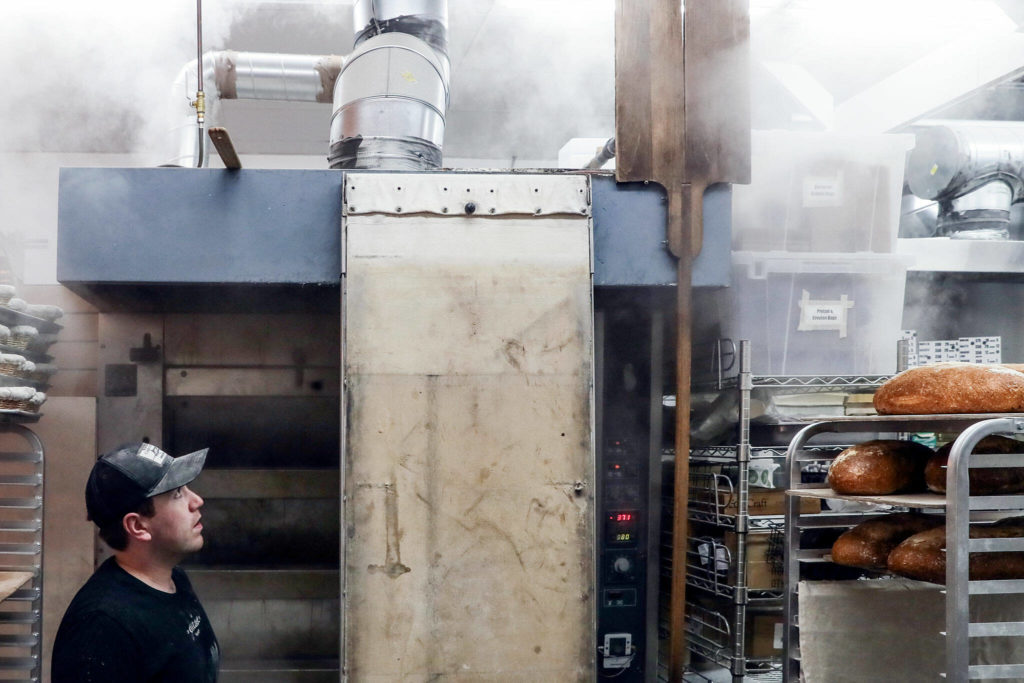 Conor O’Neill watches steam rising from his decked oven Friday morning at The Cottage Community Bakery on Sept. 30, in Edmonds. (Kevin Clark / The Herald)
