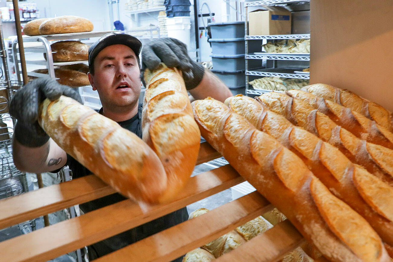 Conor O’Neill racks freshly baked baguettes Friday morning at The Cottage Community Bakery in Edmonds, Washington on September 30, 2022.  (Kevin Clark / The Herald)