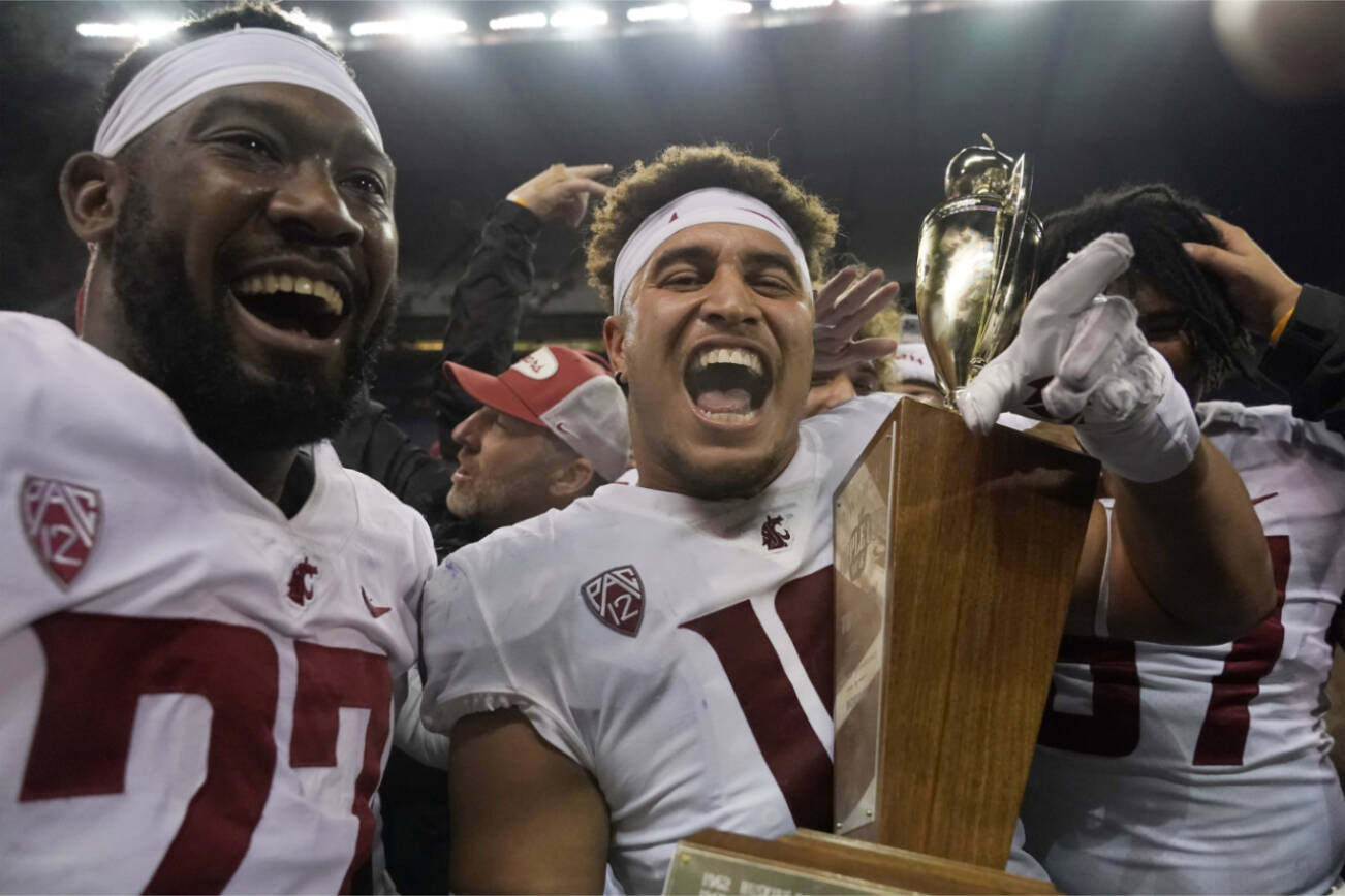 Washington State defensive end Ron Stone Jr., center, celebrates with Willie Taylor III, left, as he holds the Apple Cup Trophy after they defeated in an NCAA college football game, Friday, Nov. 26, 2021, in Seattle. (AP Photo/Ted S. Warren)