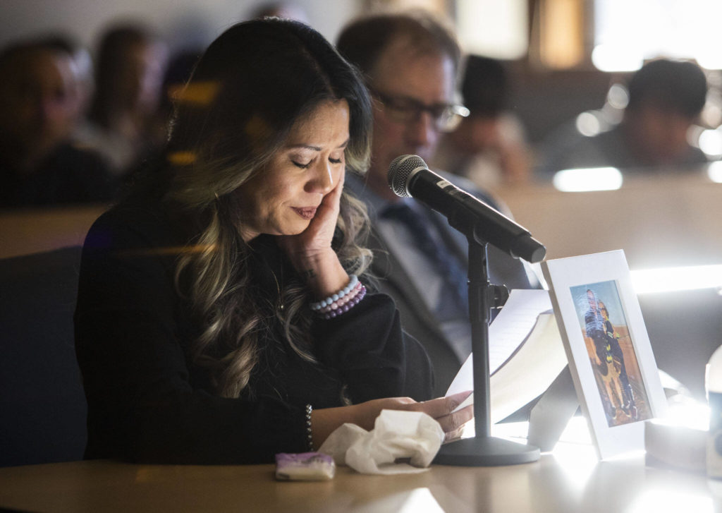 Sunlight illuminates a framed photograph of Mila and Wilfrido Sarmiento while their daughter Rowella Sarmiento cries reading her statement to the court during Caleb Wride’s sentencing on Monday, Nov. 28, 2022 in Everett, Washington. (Olivia Vanni / The Herald)
