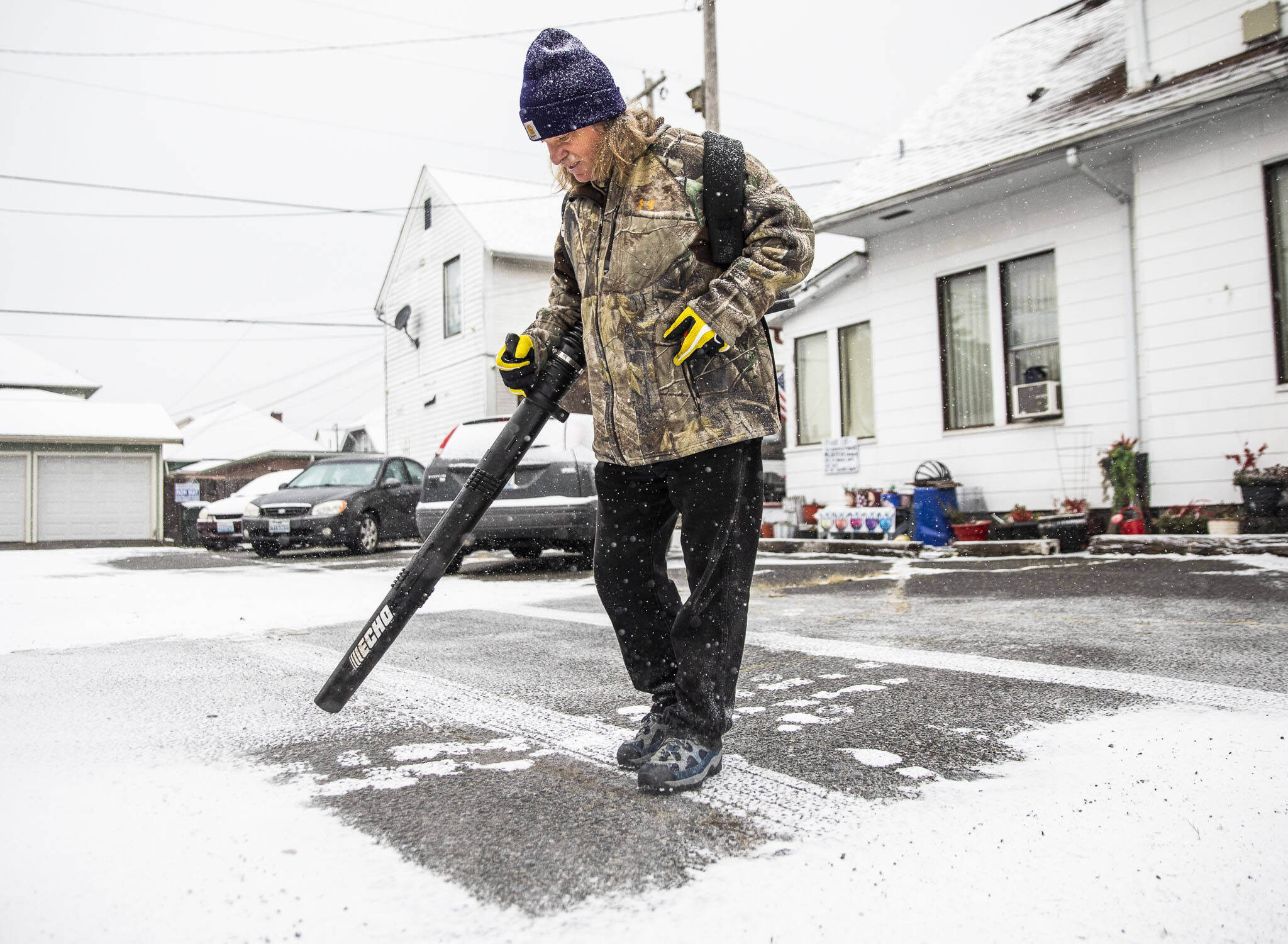 Robert Miller blows snow out of the parking lot next to his home as snow comes down on Tuesday in Everett. (Olivia Vanni / The Herald)