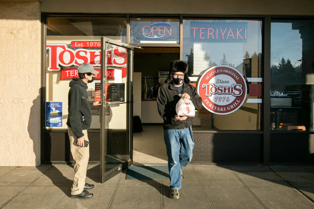 A customer holds the door for Rick Cote as he leaves with food for himself and his family at Toshi’s Teriyaki Grill in Mill Creek. (Ryan Berry / The Herald)

