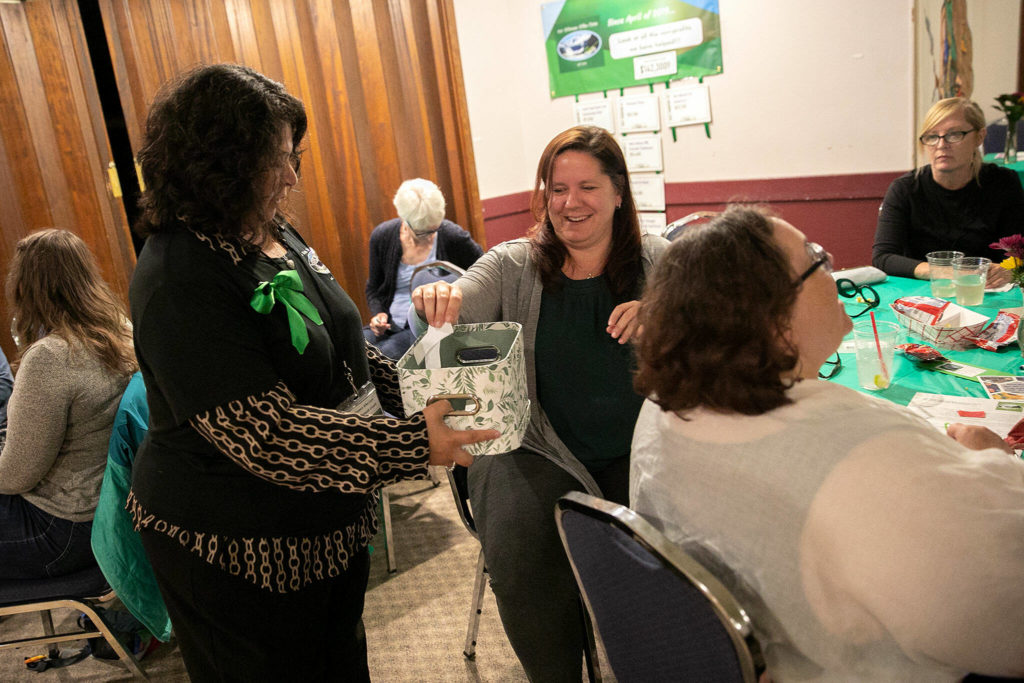 Members of 100+ Women Who Care About Snohomish County put their votes in a basket during their Giving Circle meeting at the Sons of Norway Normanna Lodge in Everett. (Ryan Berry / The Herald)
