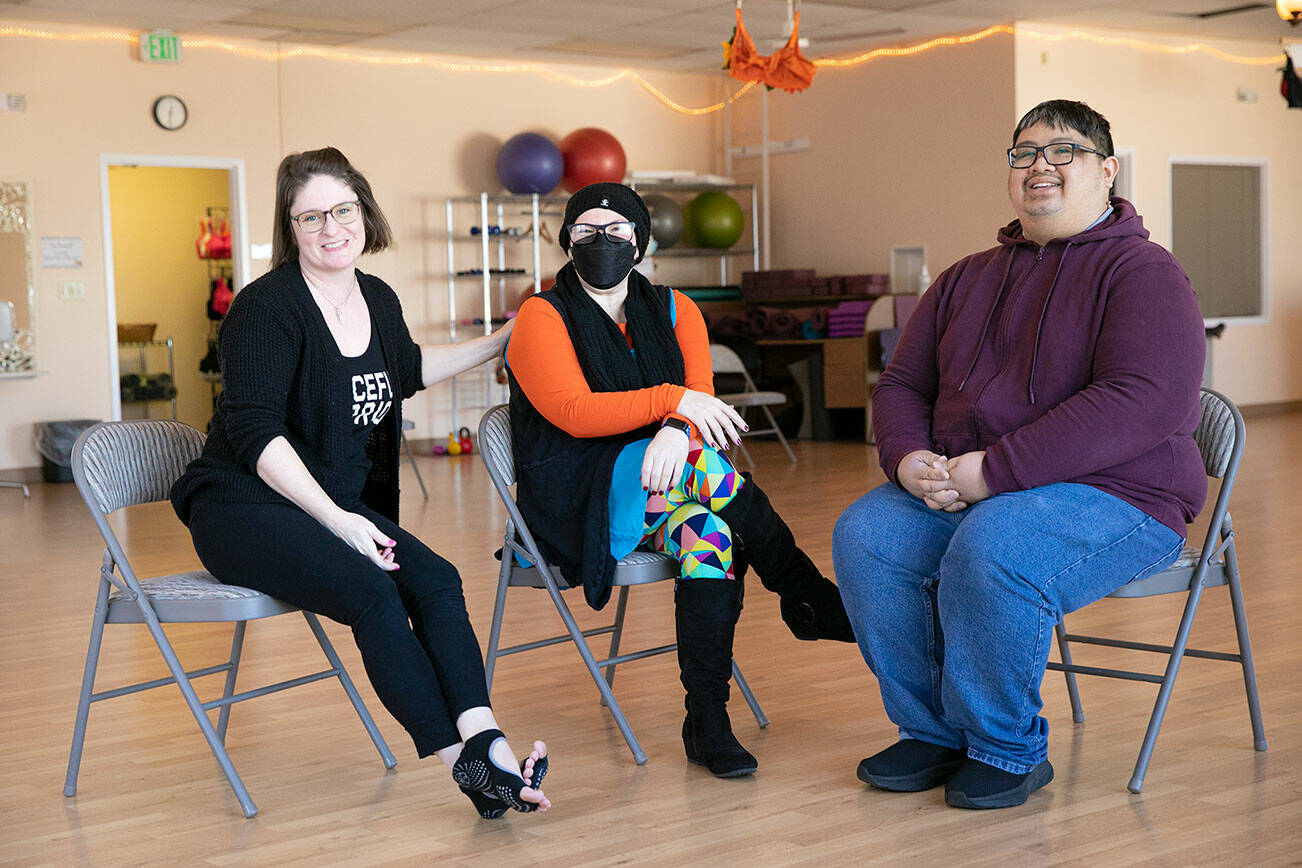 Emma Gardner, Lauren Mallams and Lionel Bongon, who are only a few of Citrine Health’s many staff members, sit together in the yoga studio at Citrine Health on Wednesday, Nov. 9, 2022, in Everett, Washington. (Ryan Berry / The Herald)