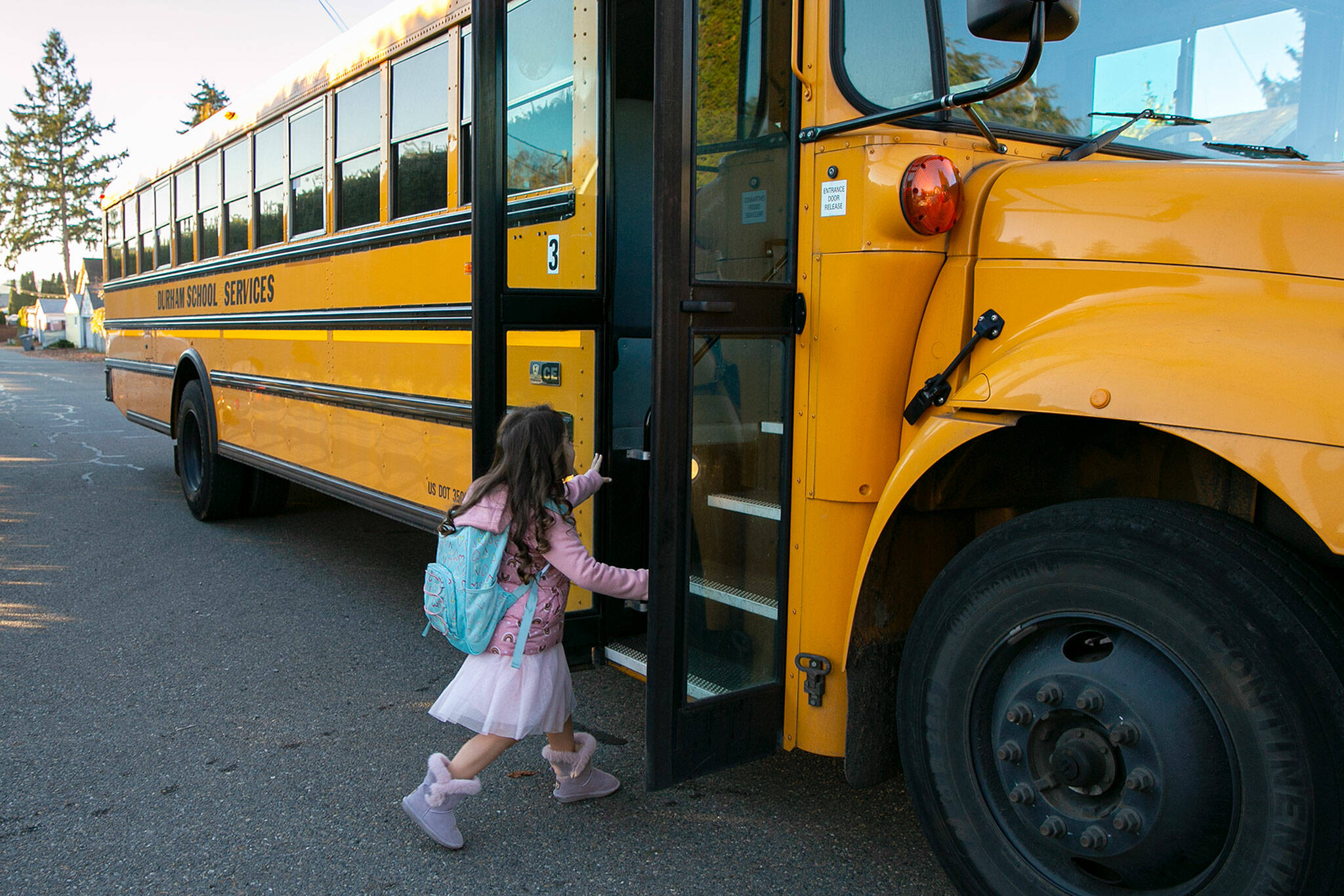 Kindergartener Jaecy Stahl heads up the stairs of an ISA bus after kissing her mother, Amy Leno, goodbye on Nov. 18, in Everett. (Ryan Berry / The Herald)