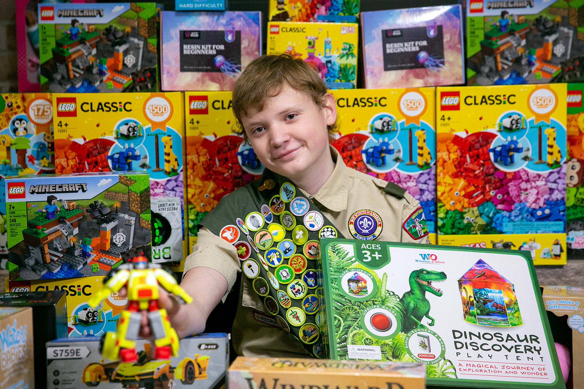 Skyler MacKay, 14, sits among some of the over 700 toys he has collected for local children in foster care as part of his Eagle Scout project at his family’s home in Lynnwood. (Ryan Berry / The Herald)