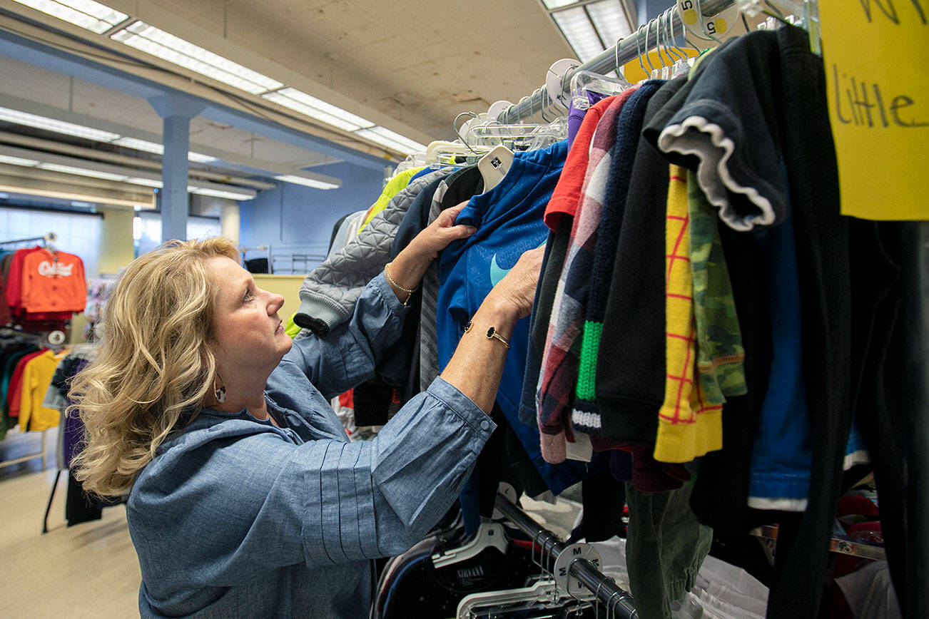 Director and Cofounder Kimberly Meno hangs up some new clothing at Arlington Kids’ Kloset on Thursday, Nov. 17, 2022, in Arlington, Washington. (Ryan Berry / The Herald)