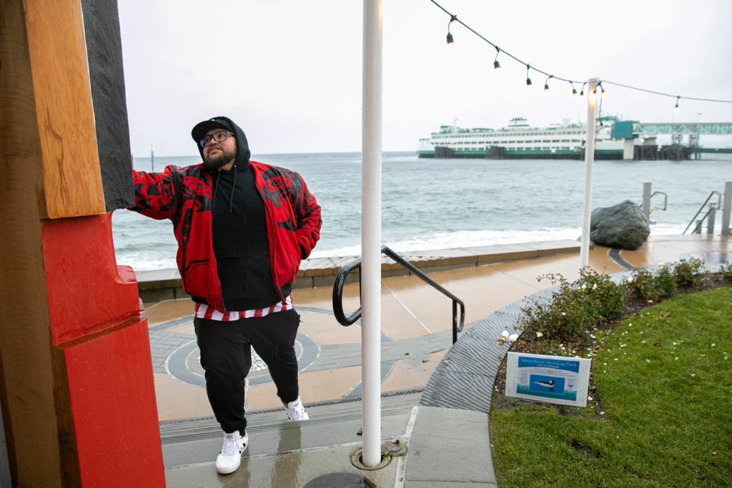 Ty Juvenil points to a few of the features of the wooden statue, which faces the Edmonds-Kingston ferry. (Ryan Berry / The Herald)
