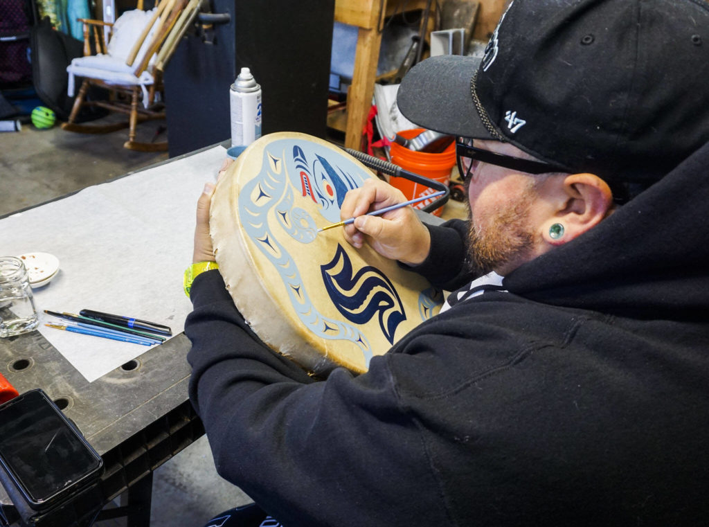 Ty Juvinel paints a traditional drum in his workshop on Wednesday, Dec. 1, 2022 in Tulalip, Washington. (Kayla Dunn / The Herald)
