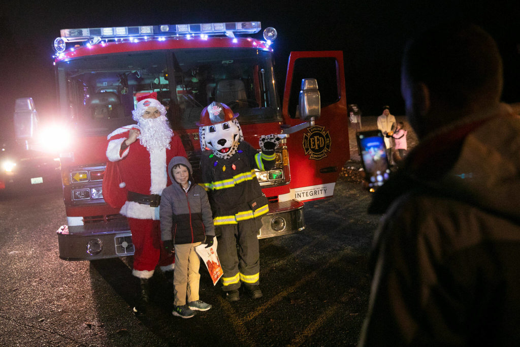 Nine-year-old Ethan Taylor gets his photo taken with Santa and a Dalmatian by his father, Ryan, as the Everett Fire Department teams up with Santa to visit children on opening night at Wintertide Lights. (Ryan Berry / The Herald)
