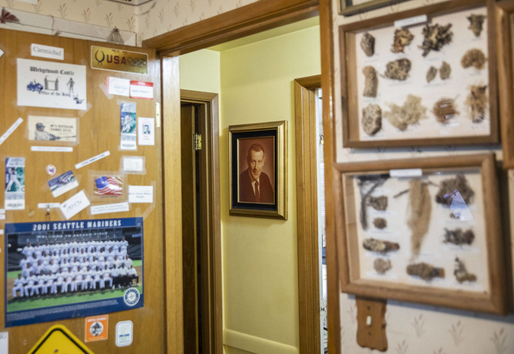 A photograph of Dr. Barry Dunphy hangs on the wall surrounded by memorabilia and hobby pieces from his hobby room in the Dunphy home on Dec. 1, in Seattle. (Olivia Vanni / The Herald) 
