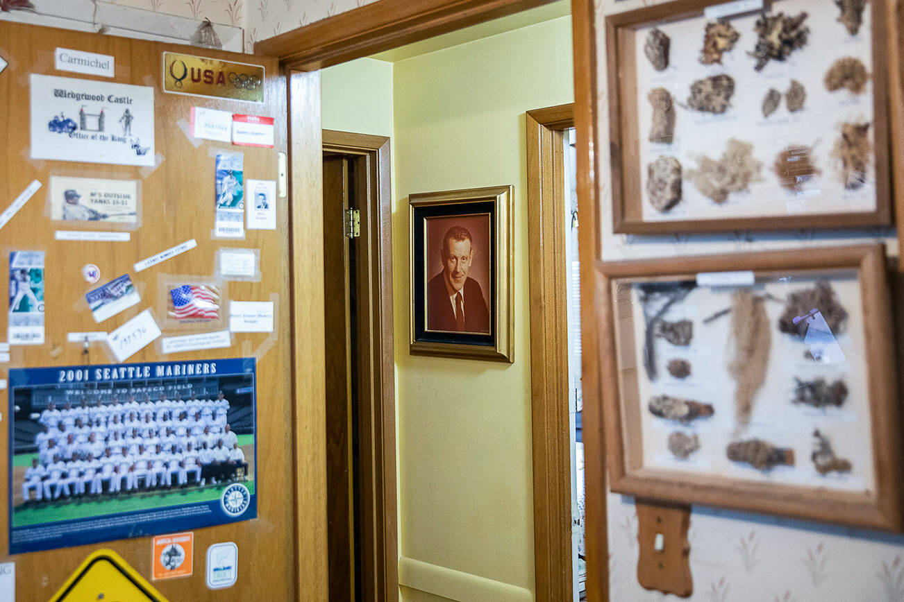 A photograph of Dr. Barry Dunphy hangs on the wall surrounded by memorabilia and hobby pieces from his hobby room in the Dunphy home on Thursday, Dec. 1, 2022 in Seattle, Washington. (Olivia Vanni / The Herald)