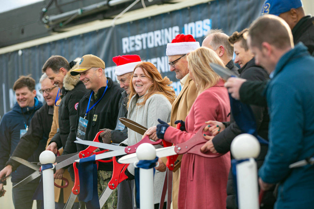 A handful of people involved in the completion of the new Norton Terminal cut a ribbon together during the dedication of the terminal on Thursday, Dec. 1, 2022, at the Port of Everett in Everett, Washington. (Ryan Berry / The Herald)
