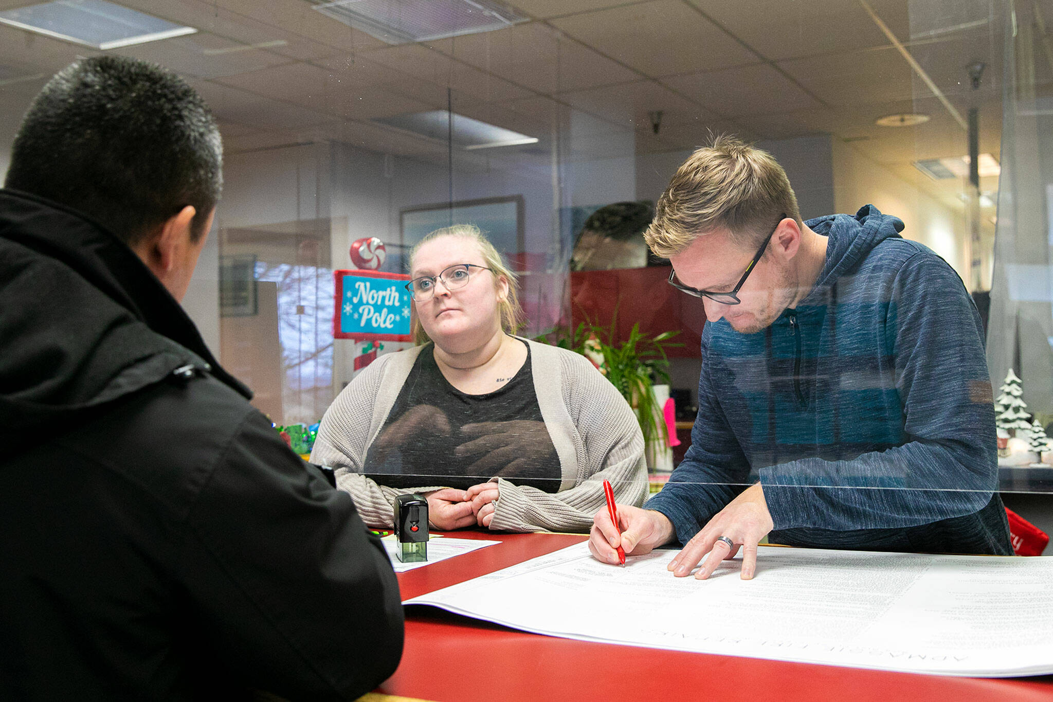 Everett permit tech Sheyenne Morton and residential plan reviewer Ryan Hammer help a general contractor with some permit application work at the Everett Public Works permit office Wednesday. The proposed 2023 budget includes additional positions for the unit. (Ryan Berry / The Herald)
