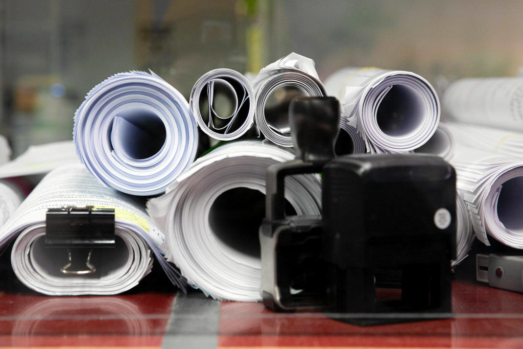 Dozens of incoming and outgoing permit documents are lined up on a table at the Everett Public Works permit office Wednesday. Additional staff in the proposed 2023 budget could help address the turnaround time for permit applications. (Ryan Berry / The Herald)
