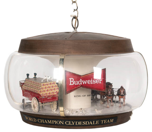 This advertising lamp includes figures of a team of horses pulling a beer cart with drivers, followed by a crowd of Dalmatians. Similar scenes may take place in real life on Budweiser’s promotional tours. The lamp with a moving wagon sold for $625.