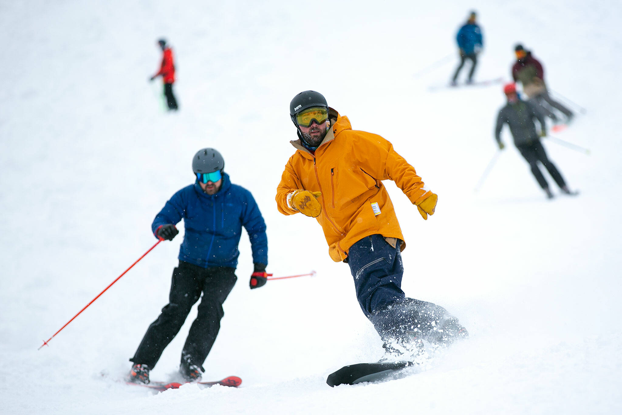 A snowboarder leads a line of skiers to the bottom of the hill on the opening day of ski season at Stevens Pass Ski Area on Friday. (Ryan Berry / The Herald)