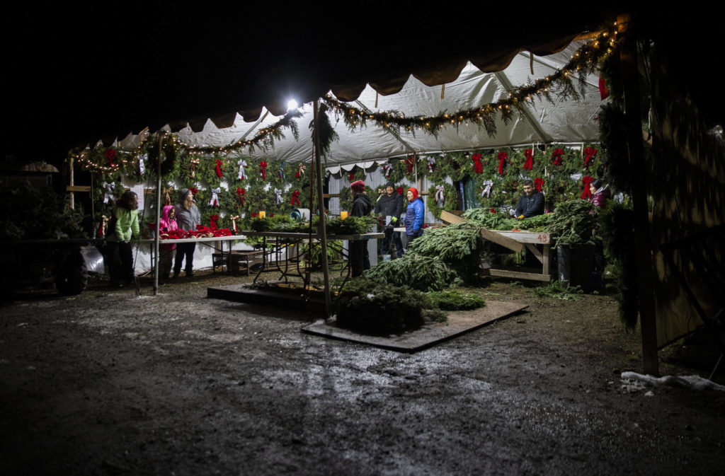 The Montano and Rodriguez families work together to assemble wreaths on Dec. 5, in Monroe. (Olivia Vanni / The Herald)
