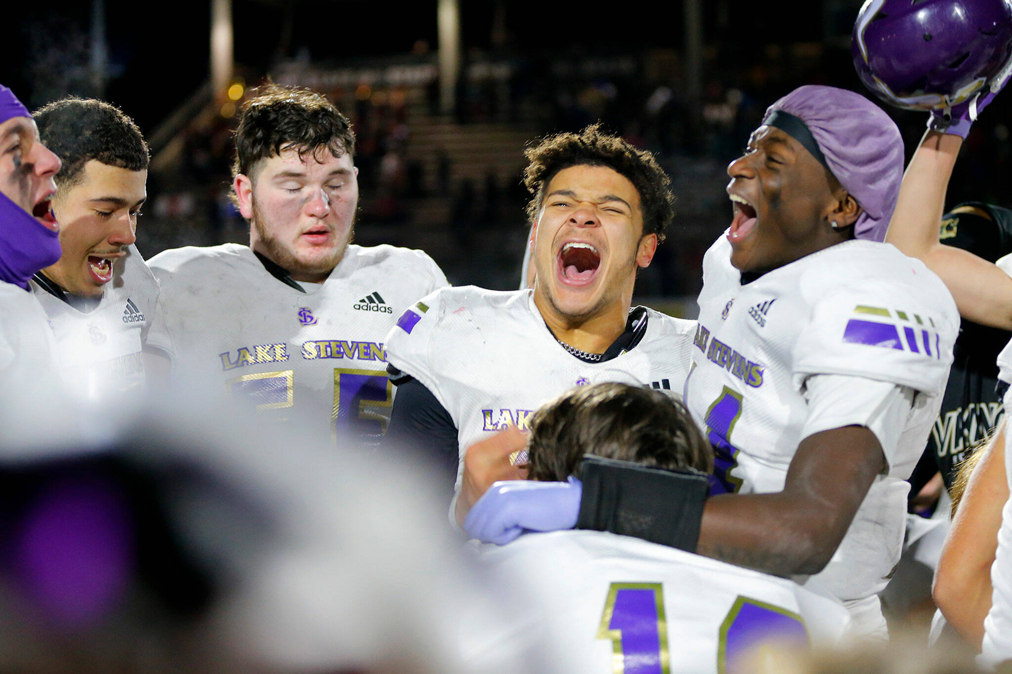 Jayden Limar (center) and Isaac Redford (right) celebrate with teammates after Lake Stevens claimed its first-ever state title with a 24-22 win over Kennedy Catholic in the Class 4A state championship game Saturday night. (Ryan Berry / The Herald)
