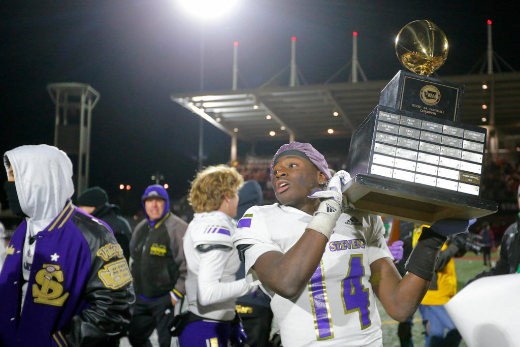 Lake Stevens’ Isaac Redford looks to hand off the WIAA 4A State Football Championship trophy to a coach while celebrating his team’s win Saturday, Dec. 3, 2022, at Mount Tahoma Stadium in Tacoma, Washington. (Ryan Berry / The Herald)
