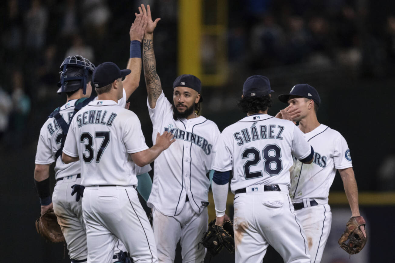 Seattle Mariners players including, from left, Cal Raleigh, Paul Sewald, J.P. Crawford, Eugenio Suarez and Adam Frazier celebrate after a baseball game against the Chicago White Sox, Tuesday, Sept. 6, 2022, in Seattle. The Mariners won 3-0. (AP Photo/Stephen Brashear)