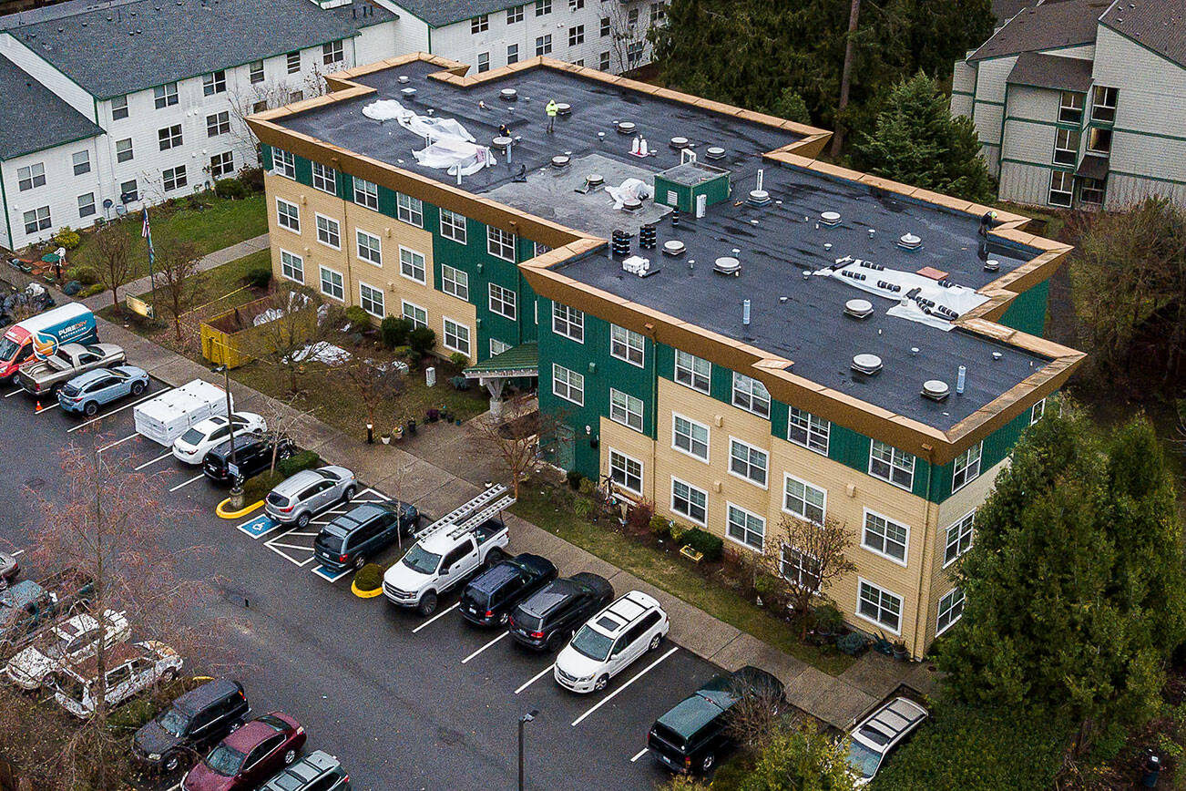 People work on the roof of the Stilly Valley Senior Center on Thursday, Dec. 8, 2022 in Arlington, Washington. (Olivia Vanni / The Herald)