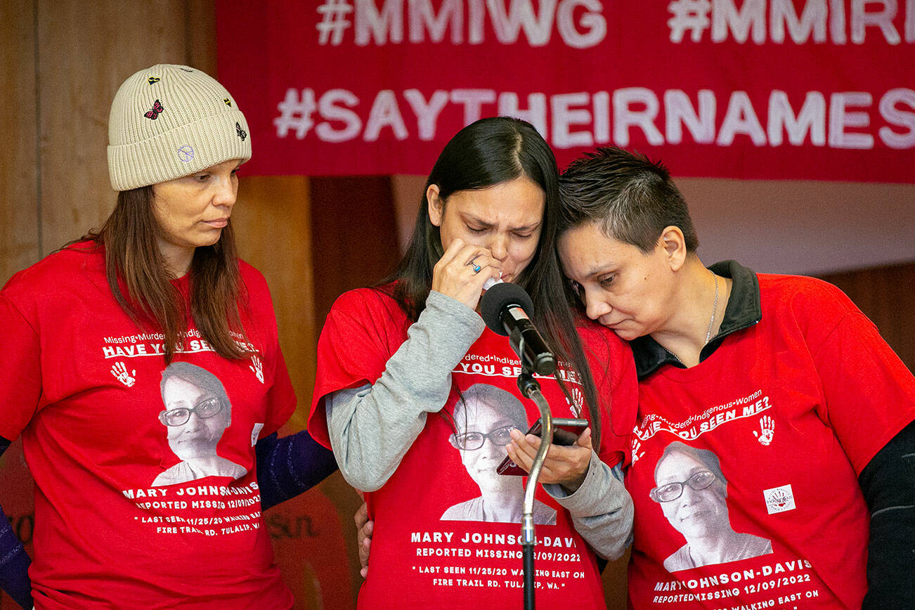 Gerry Davis, supported by sisters Sara, left, and Nona Blouin, reads a statement asking for help in the search for their missing sister, Mary Ellen Johnson-Davis, during a gathering marking two years since her disappearance in Snohomish County on Sunday, Dec. 11, 2022, at Daybreak Star Indian Cultural Center in Seattle, Washington. (Ryan Berry / The Herald)