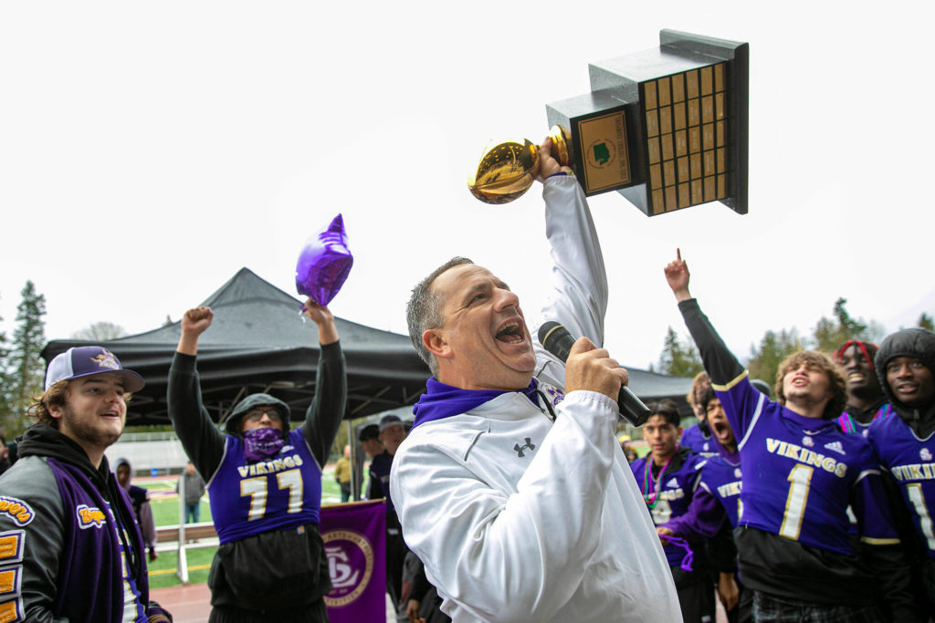 Lake Stevens High School head football coach Tom Tri hoists his team’s championship trophy during a community parade and celebration Saturday, Dec. 10, 2022, in Lake Stevens, Washington. (Ryan Berry / The Herald)
