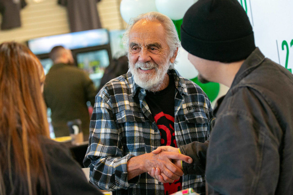 Tommy Chong shakes hands with Selena Morales and Elijah Harrison, both of Arlington, after taking a photo with them and giving them a couple signatures during 210 Cannabis Co’s grand opening Dec. 10, in Arlington. (Ryan Berry / The Herald)
