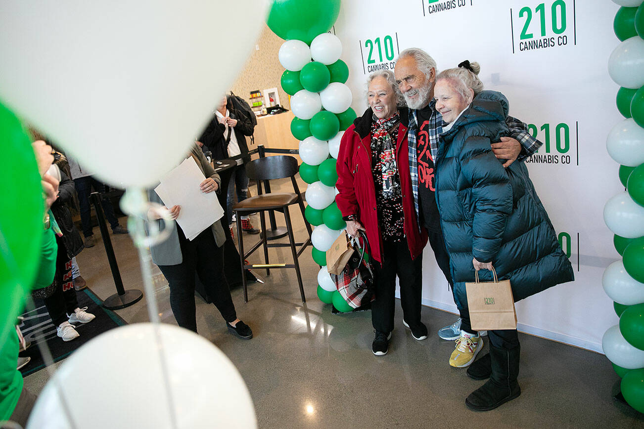 Carla Fisher and Lana Lasley take a photo together with Tommy Chong during 210 Cannabis Co’s grand opening Saturday, Dec. 10, 2022, in Arlington, Washington. Fisher and Lasley waited in line solely to get a photo with Chong. (Ryan Berry / The Herald)