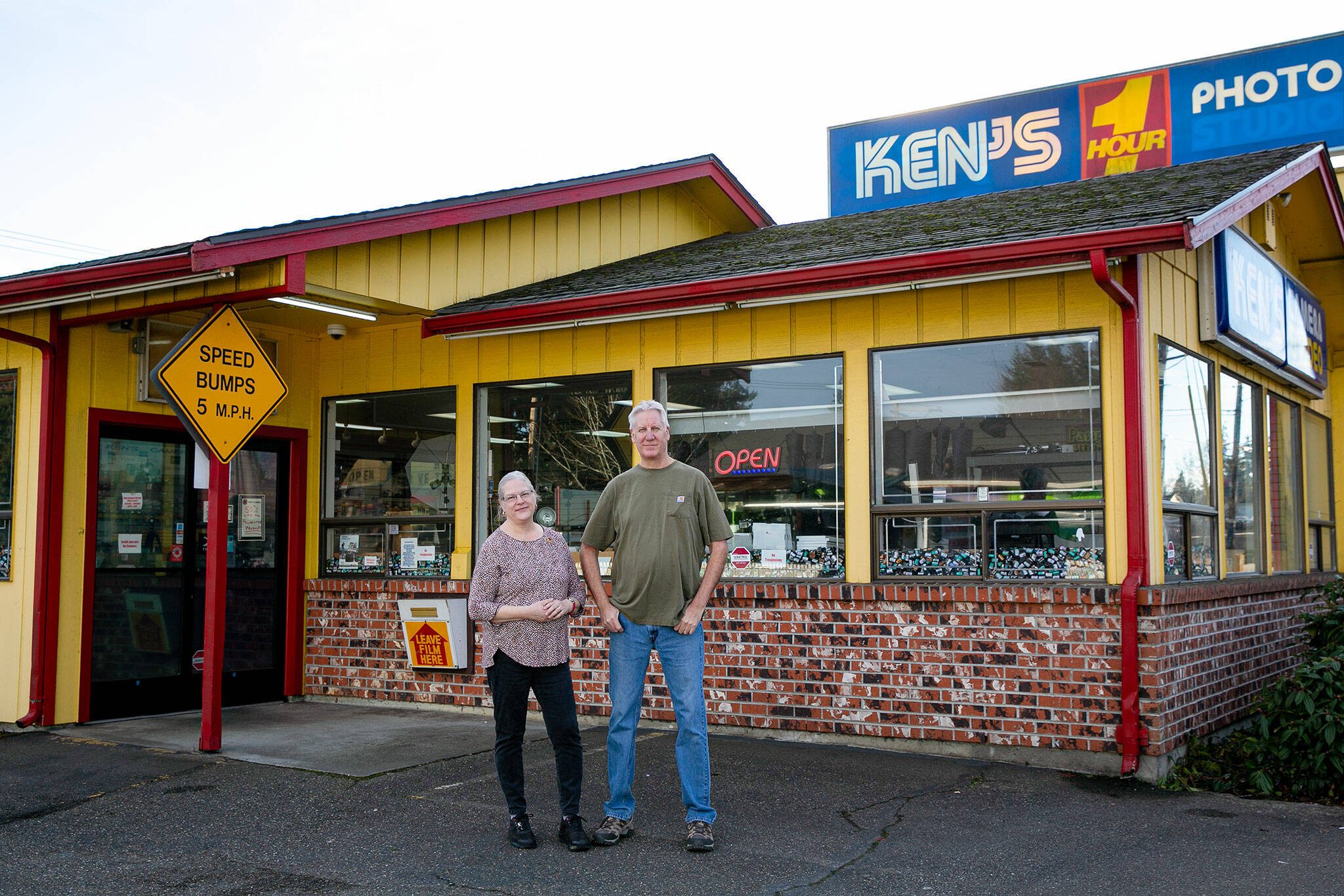 Siblings Barbara Reed and Eric Minnig, who, co-own their parent’s old business Ken’s Camera along with their brother Bryan, stand outside the Evergreen Way location Thursday, Dec. 15, 2022, in Everett, Washington. After five decades in business, Ken’s will be closing its last two locations for good at the end of the year. (Ryan Berry / The Herald)