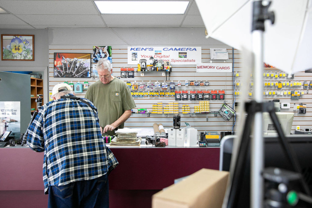 Eric Minnig, co-owner of Ken’s Camera, takes care of a customer who stopped in to get film processed Thursday, Dec. 15, 2022, in Everett, Washington. (Ryan Berry / The Herald)
