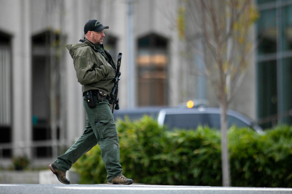 An armed member of law enforcement walks outside the Snohomish County Superior Courthouse during a lockdown Monday, in downtown Everett. (Ryan Berry / The Herald)
