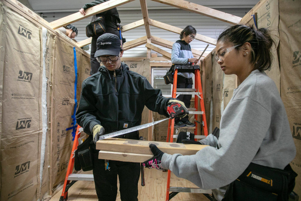 Students Darian Vandee and Angelica Subillaga get their measurements right while working inside a tiny home they and classmates are working on for their pre-apprenticeship program Monday, Dec. 12, 2022, at the Washington Aerospace Training & Research Center in Everett, Washington. (Ryan Berry / The Herald)

