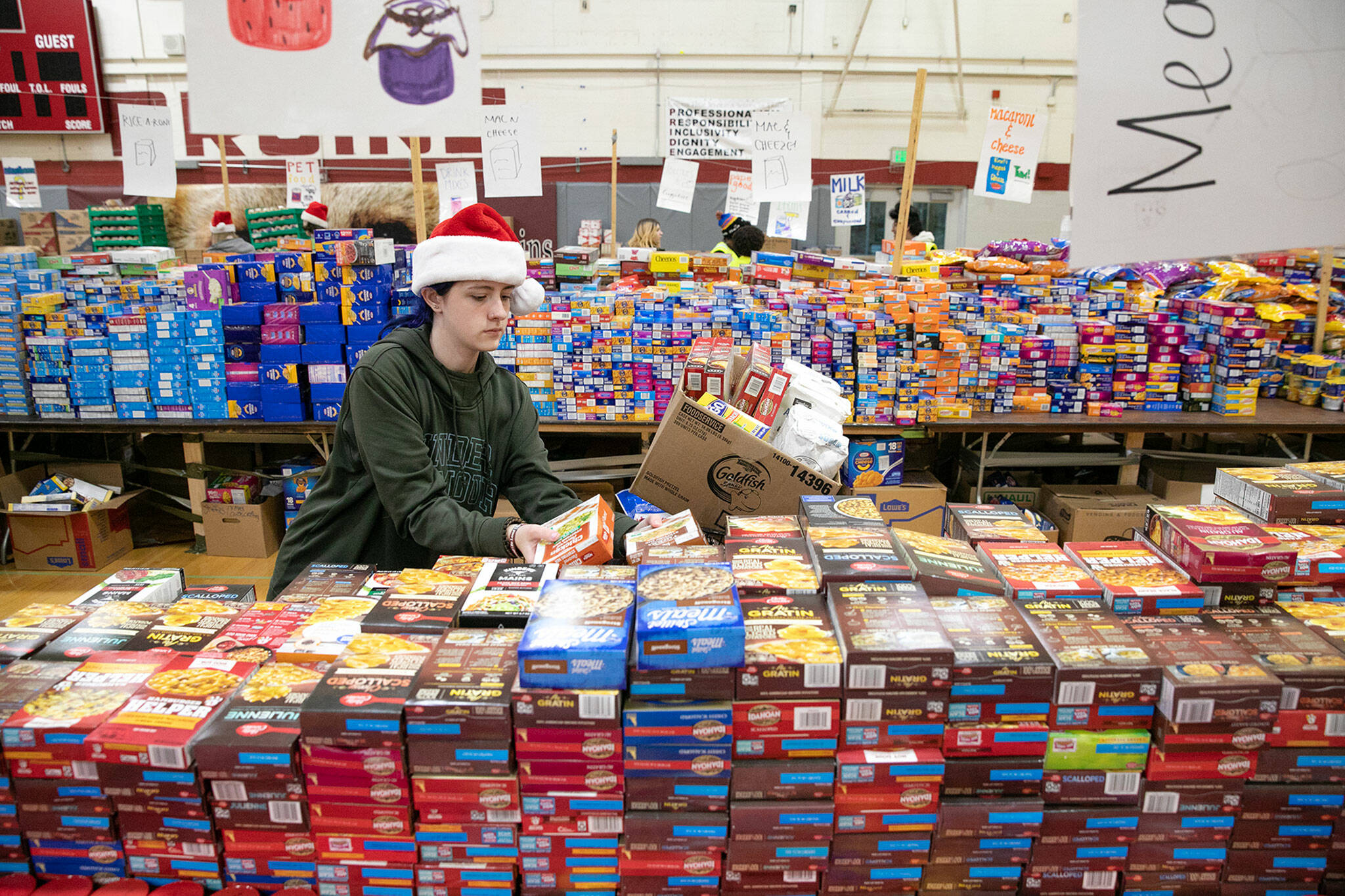 Cascade freshman Trinitee Austad weaves through aisles of food and fills a few boxes for a family in need during Cascade’s annual holiday food drive Wednesday, Dec. 14, at Cascade High School in Everett. (Ryan Berry / The Herald)
