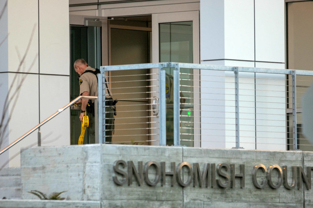 A member of the sheriff’s office puts up police tape at the Snohomish County Courthouse after an armed intruder forced a lockdown Monday, in downtown Everett. (Ryan Berry / The Herald)
