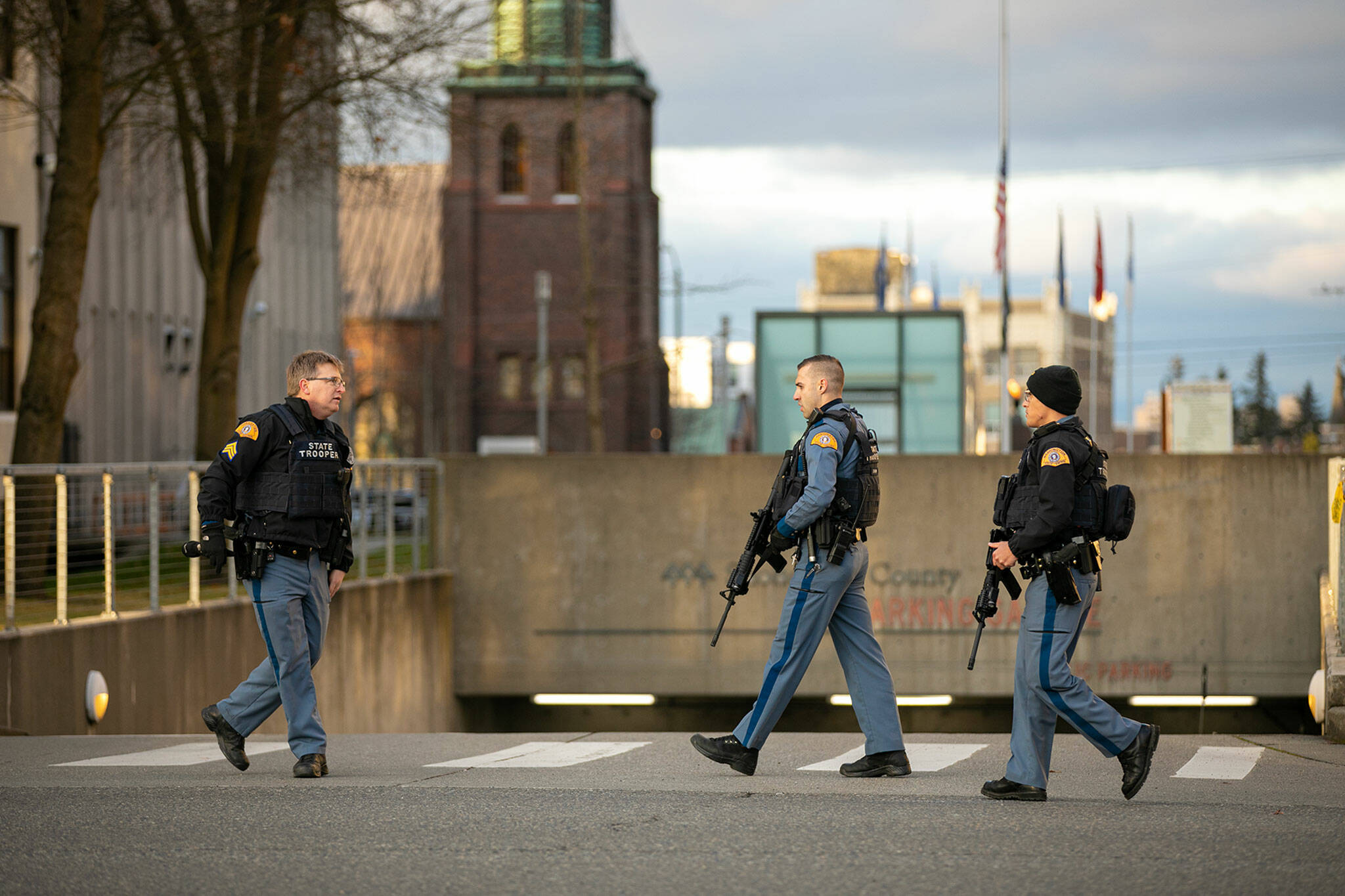 Three state troopers get together while helping civilians get their cars out of the parking garage during a lockdown at the Snohomish County Courthouse on Monday, in downtown Everett. (Ryan Berry / The Herald)