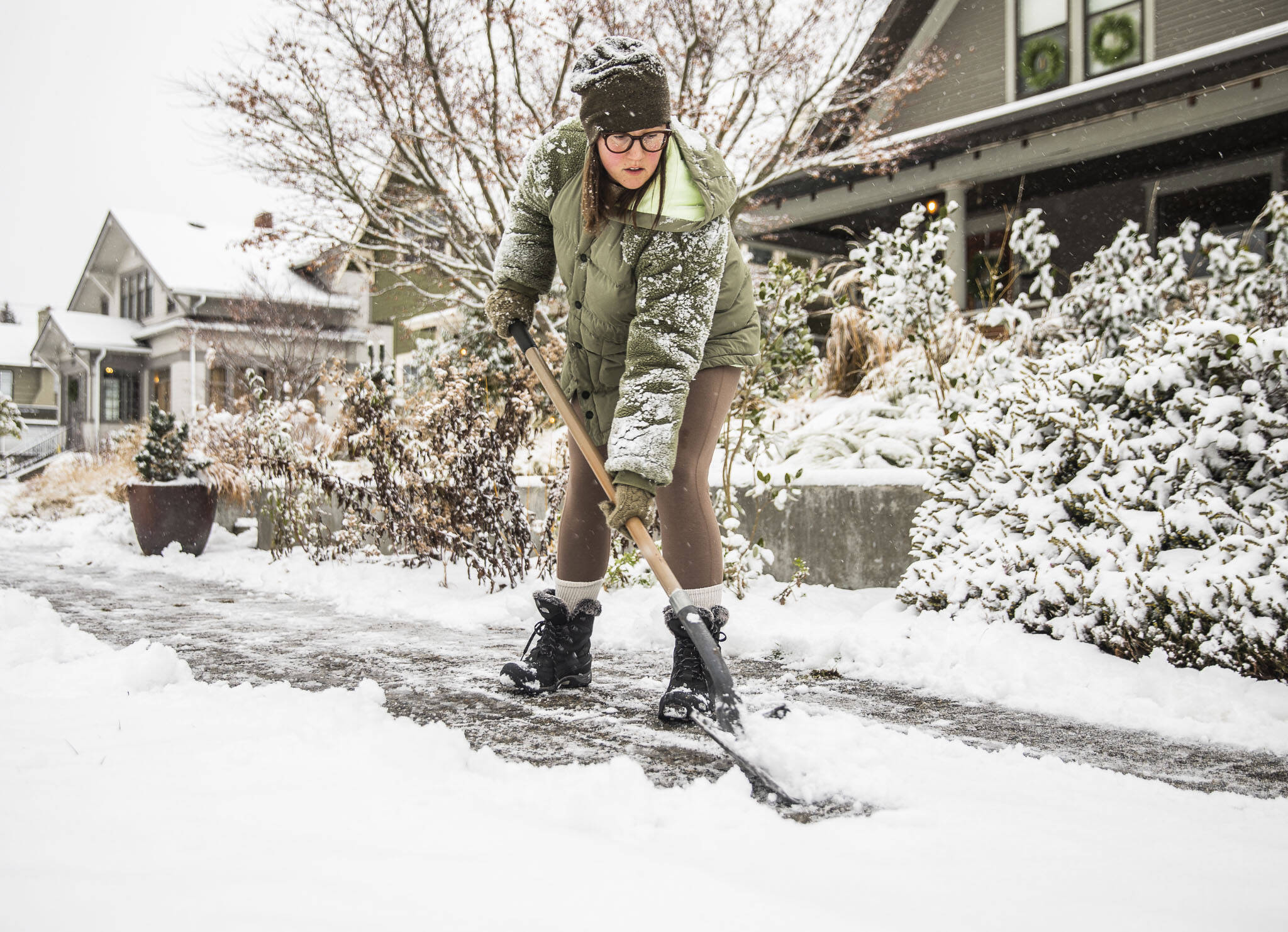 Carly McGinn shovels the sidewalk in front of her home as snow falls on Tuesday, in Everett. (Olivia Vanni / The Herald)