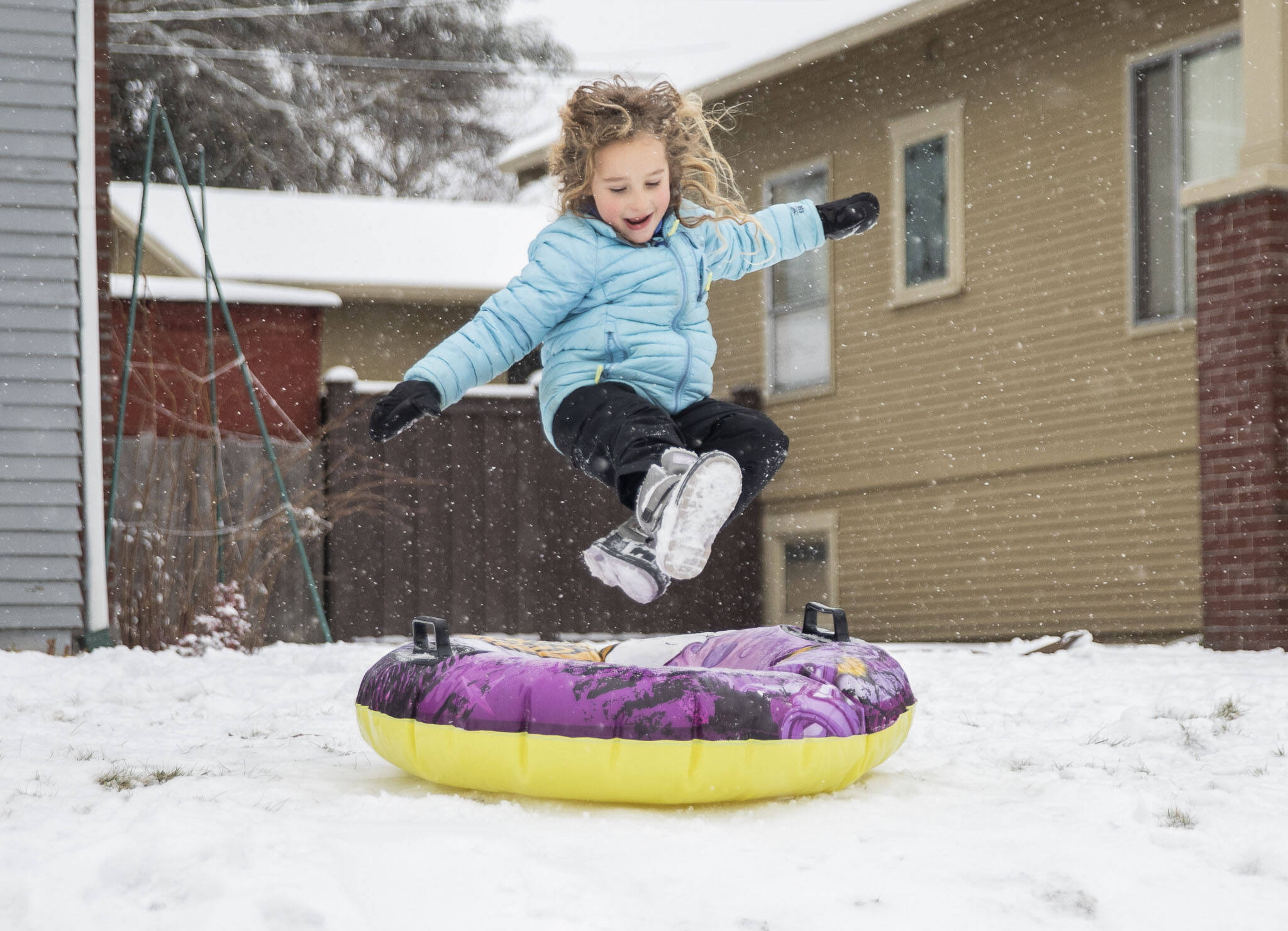 Halle Lucas-Roberts, 6, leaps onto her tube while sledding in front of her home on Tuesday, in Everett. (Olivia Vanni / The Herald)