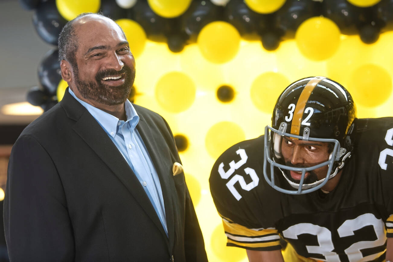 FILE - Former Pittsburgh Steelers running back Franco Harris stands next a statute of himself on Sept. 12, 2019, at Pittsburgh International Airport near Pittsburgh. Harris died on Wednesday morning, Dec. 21, 2022, at age 72, just two days before the 50th anniversary of The Immaculate Reception. (Nate Guidry/Pittsburgh Post-Gazette via AP, File)