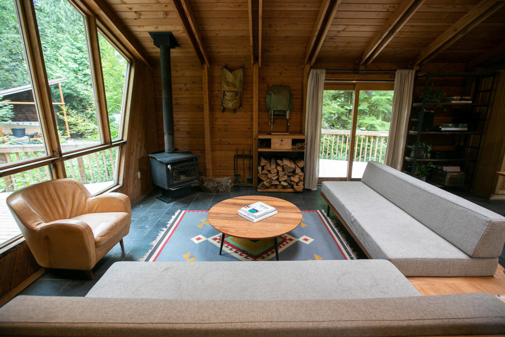 The living space in Cabin 1 is furnished with seating built by co-owner Andy Whitcomb at Canyon Creek Cabins on Sep. 23, in Granite Falls. (Ryan Berry / The Herald)
